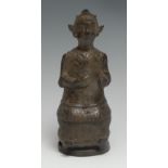 Chinese School, a patinated bronze figure, of an ancestral deity, seated holding a mirror, wearing