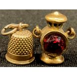 A miniature yellow metal railway signal lamp charm; a miniature thimble charm