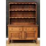 An oak dresser, moulded cornice above a pair of plate racks, the base with two short drawers above