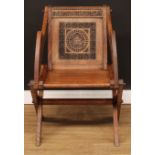 An Arts & Crafts period Gothic Revival oak Glastonbury chair, the back carved with leaves, flower