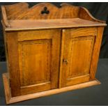 An Arts and Crafts oak smoking room cabinet, shaped and pierced three-quarter gallery above a pair