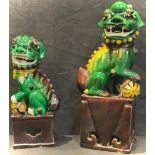 A Chinese Dog of Fo, glazed in green and brown, 30cm; another smaller, typically glazed, 24cm (2)