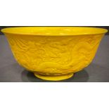 A Chinese yellow glazed bowl, decorated in relief with dragons, 15.5cm diameter