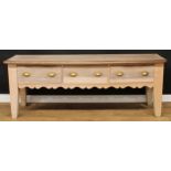 A large farmhouse pine and softwood low dresser or serving table, oversailing top above three frieze