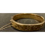 A 9ct gold hinged bangle, safety chain, marked 375, 20.7g