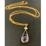 A diamond and pale blue stone pendant necklace, oval pale blue droplet suspended from a round