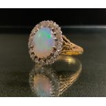 An opal and diamond cluster ring, central oval opal cabochon, vibrant green violet and red colour