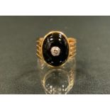 A diamond and black onyx signet ring, oval black onyx cabochon inset with a single round brilliant