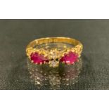 An Edwardian ruby and diamond ring, set with a pair of old cut diamonds between pear drop vibrant