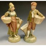 A pair of Royal Dux figural spill vases, Farm Boy and Girl, each with basket apertures, pink