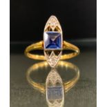 An Art Deco diamond and purply blue stone ring, central square blue stone between round brilliant