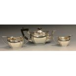 A silver three piece panelled boat shaped tea service, ebonised button final, angular handle,