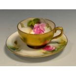 A Royal Worcester cabinet cup and saucer, decorated with roses, the exterior in gilt, crown and