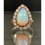 An opal and diamond ring, large pear cabochon opal, flashing vibrant green, blue and violet colour