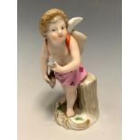 A Meissen figure, of a cherub, holding a fish, a net on his back, 10cm high, crossed swords, painted