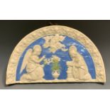 A Della Robbia style semi-circular plaque, moulded in high relief with the Annunciation, within a