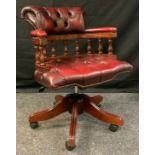 A captains revolving desk chair, in oxblood leather, five point base, castor feet, 86cm high, 60cm