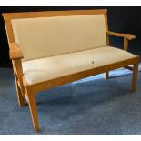 A 20th century light oak settle, upholstered seat and back, 128cm wide x 52cm depth x 87cm tall. (