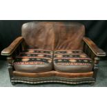 An unusual early 20th century oak and tooled leather salon sofa, double serpentine front, tan