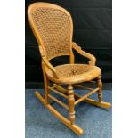 A 19th century Beechwood rocking chair, arched back, turned stretchers, woven seat and back, 93cm