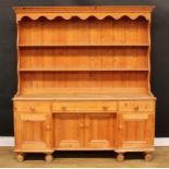 A Victorian design farmhouse pine dresser, shaped apron above two shelves, the projecting base
