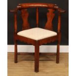 A George III walnut and mahogany corner chair, curved arms terminating in outswept hand rests,