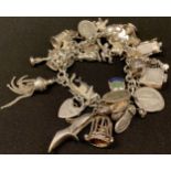 A silver charm bracelet full of charms, including vintage motor car, birdcage, stein, swan, shoes,