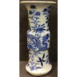 A Chinese gu shaped vase, painted in tones of underglaze blue with dragons amongst flowers and