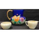 An Art Deco Carlton Ware jug, painted with bright flowers, cobalt blue ground, gilded loop handle,