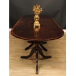 A George III Revival mahogany triple-pillar dining table, crossbanded discorectangular top, turned