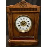 A German oak mantel clock, arched case, white enamel dial with Roman numerals, twin winding holes,