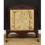 A mahogany fire screen, arched cresting carved in the Art Nouveau taste, woolwork banner, stiff
