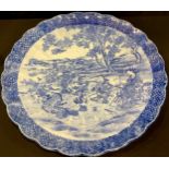 A large Japanese blue and white scalloped charger, decorated with musicians, 41cm diameter