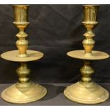 A pair of Dutch brass Heemskerk candlesticks, cylindrical sconces, broad central drip pans,