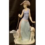 A Lladro figure, Elegant Promenade, as a fashionable lady in wide brimmed hat walking a pair of