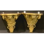 A pair of Louis XIV style gold painted wall brackets, shaped serpentine plateau above ribbon tied
