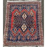 A Middle Eastern wool rug or carpet, geometric guls and lozenges in tones of blue, red and ochre,