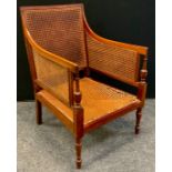 An early 20th century mahogany bergere armchair, single caned back and seat, turned fore legs,