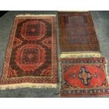 A Middle Eastern woollen rug, in tones of red, 155cm x 91cm; others, 80cm x 117cm; a prayer mat,