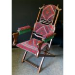 A late Victorian Baveystock patent bustle back campaign chair, upholstered in red and blue geometric