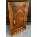 An 18th century oak corner cupboard, c.1790 moulded cornice above arched field panelled door, H