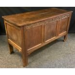 An 18th century oak blanket box, c.1760 planked top, three panelled front, the frieze carved with