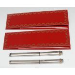 A pair of Must de Cartier Vendome pens, fountain and ball point, 14cm long, red wallets, c. 1994