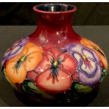 A contemporary Moorcroft Pansy pattern compressed ovoid vase, maroon ground, tube lined, 10cm high