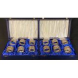 A set of twelve silver napkin rings in two fitted cases, Birmingham 1990, 296g