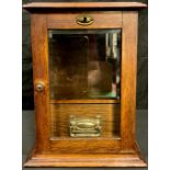 An Edwardian oak smoker's cabinet, hinged cover, glazed door enclosing pipe rack and single