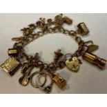 A 9ct gold curb link charm bracelet, love heart clasp, assorted charms including miner's lamp,