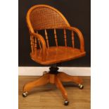 A Victorian style swivel desk chair, arched back with bergère cane panel, downswept arms, turned