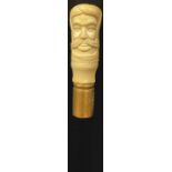 A contemporary carved bone handled walking stick, the handle as the head of an elder, 91cm long