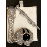 An Arts and Crafts mask brooch; a silver and marcasite Elephant brooch; a silver clarinet